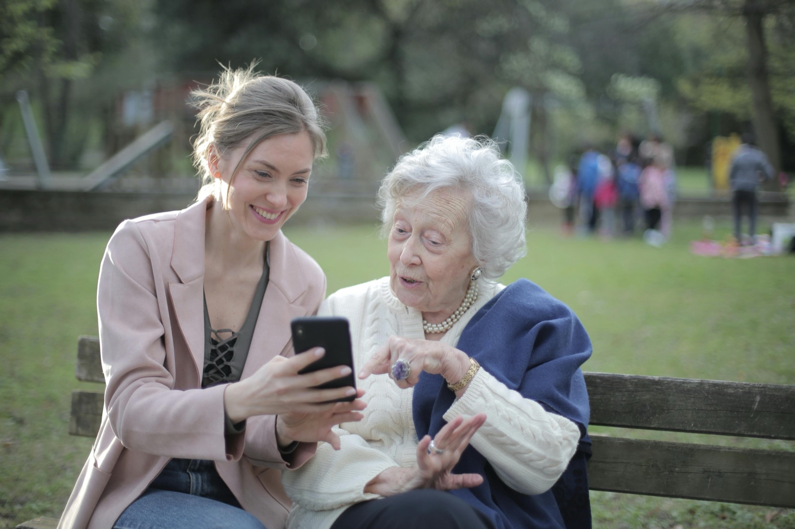 A family member helping a senior review program information on a phone